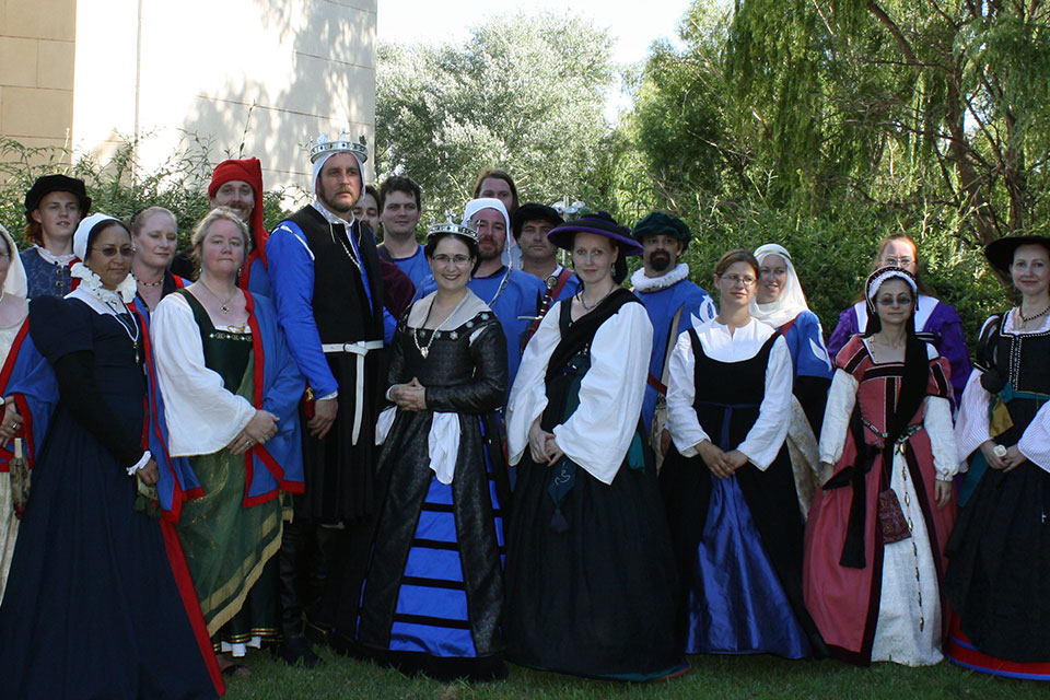 group of people standing in a park, dressed in medieval clothing